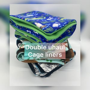 May include: A stack of folded fleece cage liners with various patterns including blue with flamingos, light blue with sloths, and white with black line art. The text Double uhaul Cage liners is overlaid on the center of the fabric stack.