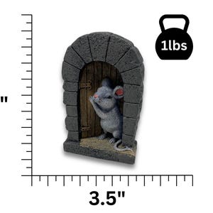 Op de afbeelding: Een grijs hars beeldje van een muis die uit een kleine stenen boog met een houten deur kijkt. Het beeldje is 15 cm hoog en 9 cm breed en weegt 450 gram.