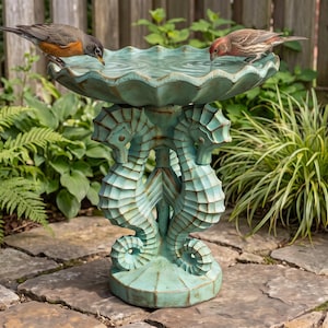May include: A teal-colored birdbath featuring a scalloped basin supported by three sculpted seahorses standing on a circular base. Two birds are perched on the rim of the basin, drinking water from the shallow, rippled pool within the structure.