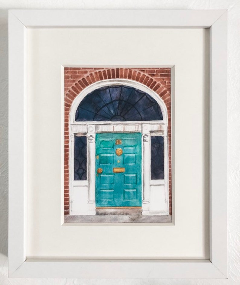 May include: A watercolour painting of a teal green door with a brass door knocker and a brass letterbox. The door is framed by a white door frame and a brick archway. The door is set against a brick wall.