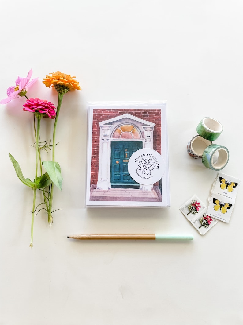 May include: A watercolor painting of a green door with a brick archway and a red brick building. The painting is on a white card with a sticker that says "Hen and Chick Art".