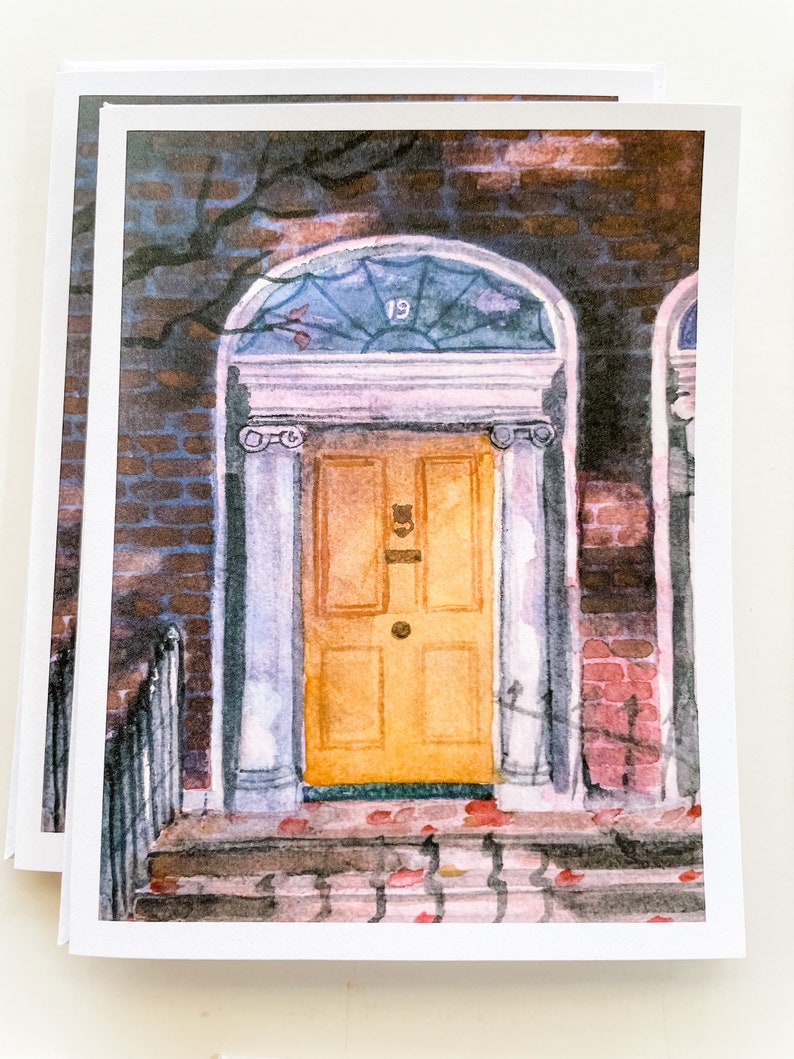 May include: A watercolor painting of a yellow door with a glass window above it. The door is framed by white columns and has a brass door knocker. The door is set in a brick wall with a vine growing up the side. The number "19" is visible on the glass window.