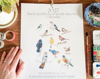 May include: A 2027 Backyard Birds of North America calendar featuring watercolour illustrations of various birds. The text reads 2027 Backyard Birds of North America Calendar, HenAndChickArt.etsy.com, Watercolour Paintings by Rachel Linquist.