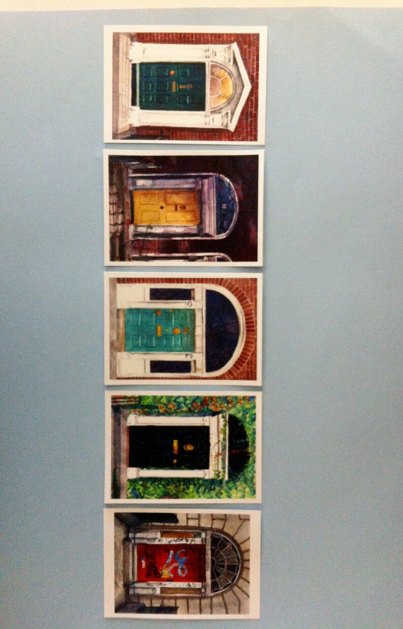 May include: Five framed watercolour paintings of colourful doors in various architectural styles. Each door is a different colour, including green, yellow, blue, black, and red.