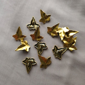 May include: Ten gold-colored metal buttons shaped like ivy leaves. The back of each button has a number, 6689, stamped on it.