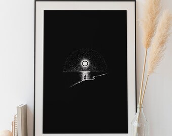 May include: Black and white print of a person standing on a beach at night with a large moon in the sky. The print is framed in a black frame and is displayed on a wooden shelf.