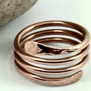 May include: A copper ring with a hammered finish, featuring a spiral design with four coils.