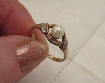 May include: A gold ring with a single pearl and small diamonds set in a delicate design.