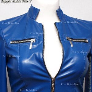 May include: Close-up of a royal blue leather jacket with a silver zipper and black zipper tape. The jacket has multiple pockets with silver zipper pulls. The text "C+K Atelier" is visible on the jacket.