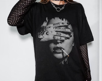 May include: Black graphic t-shirt featuring a black and white image of a person with a cigarette in their mouth. The person's hand covers their eyes, with the words "NOT FROM THE RIB" tattooed on the fingers. The shirt has short sleeves.