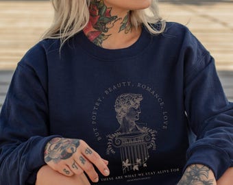 May include: Navy blue sweatshirt with a circular graphic featuring a bust, column, and text. The text reads "BUT POETRY, BEAUTY, ROMANCE, LOVE" and "THESE ARE WHAT WE STAY ALIVE FOR DEAD POETS SOCIETY."