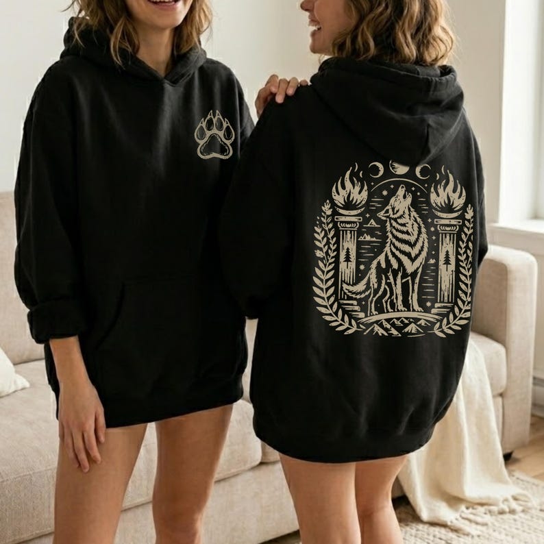Hoodie with beige howling wolf and triple moon design. Navy hoodie with same design. Maroon hoodie with back wolf design and small front paw print. Black and dark chocolate hoodies shown on models, with front and back views.
