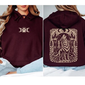 Model wearing maroon hoodie with full back wolf and moon design.