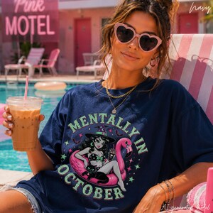Comfort Colors Halloween graphic tee featuring a retro pink flamingo float illustration with the phrase "Mentally In October." Vintage Summerween shirt designed for spooky season lovers, beach Halloween fans, and autumn enthusiasts with bold retro colors on a relaxed garment-dyed unisex t-shirt.