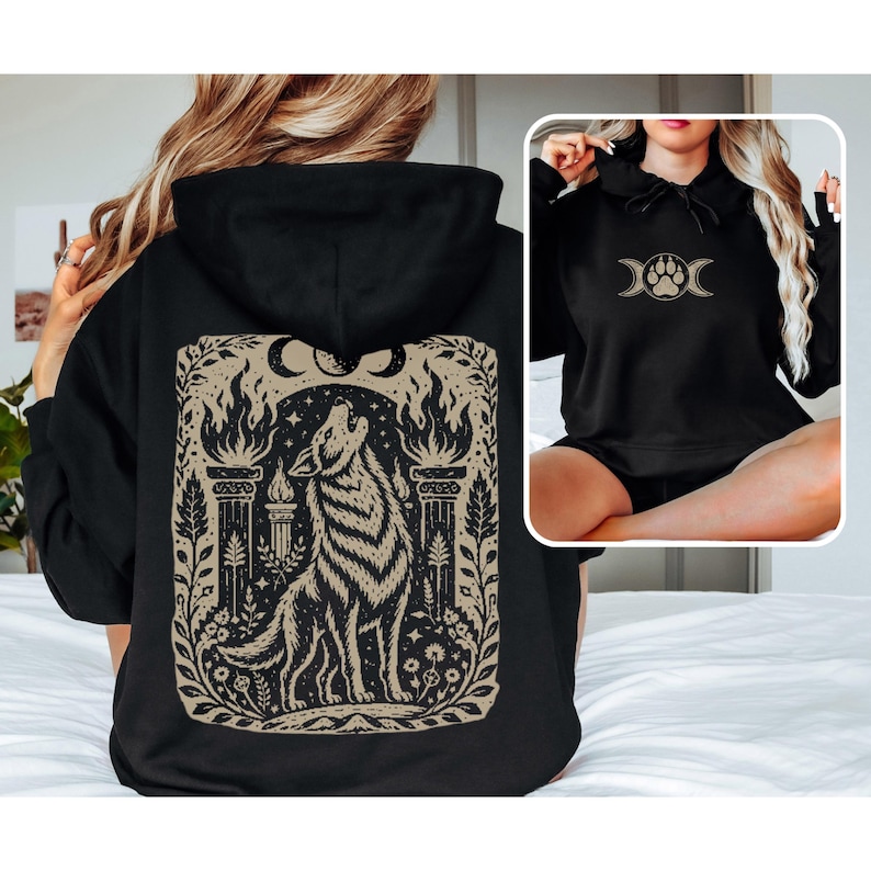 Black hoodie with linocut-style howling wolf and moon phases design on back.