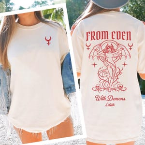May include: Cream-colored t-shirt with a red graphic on the front and back. The front features a symbol, while the back displays the text "FROM EDEN" above a red illustration of a winged figure, with the words "With Demons Lilith" below.