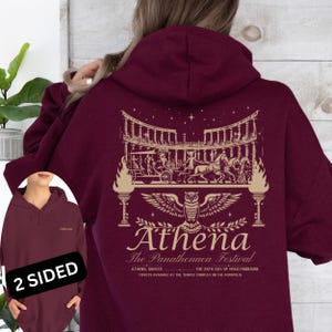 May include: Burgundy hoodie with a graphic on the back featuring an owl, architectural elements, and the text "Athena The Panathenaea Festival". The front of the hoodie has the word "Athena".