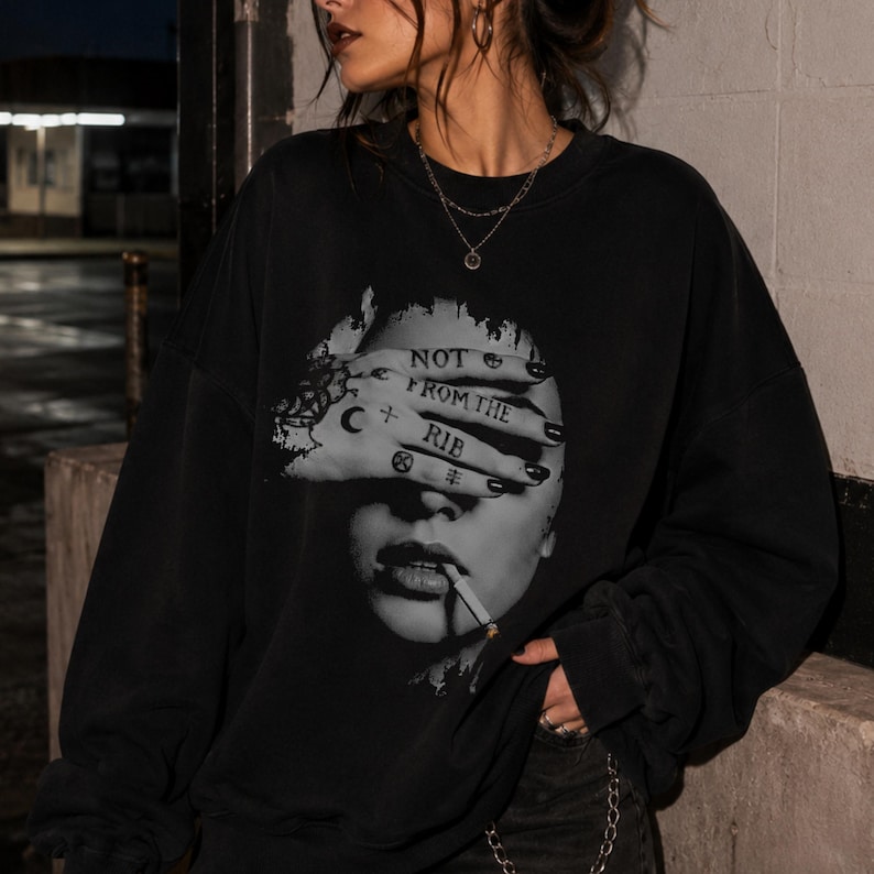 Front view of a black Gildan 18000 crewneck sweatshirt featuring a grayscale Lilith portrait, hand-over-face artwork, and “Not From the Rib” feminist quote.