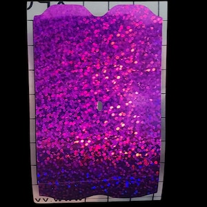 K&ouml;nnte beinhalten: Ein rechteckiger Aufkleber mit einem wellenf&ouml;rmigen oberen Rand, bedeckt mit lebendigem, funkelndem lila Glitzer. Der Glitzer hat einen Farbverlauf, der von einem tiefen Lila oben zu einem helleren, rosa Farbton zur Mitte und einem Blauton unten &uuml;bergeht.