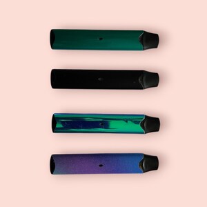 May include: Four different colored electronic cigarettes, arranged vertically on a pink background. The top cigarette is green, the second is black, the third is blue and green, and the bottom is purple.