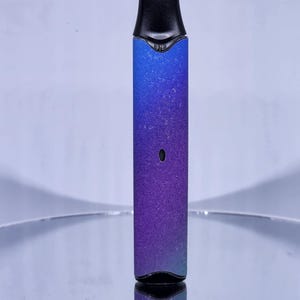 May include: A blue and purple ombre vape pen with a black mouthpiece and a black button on the side.