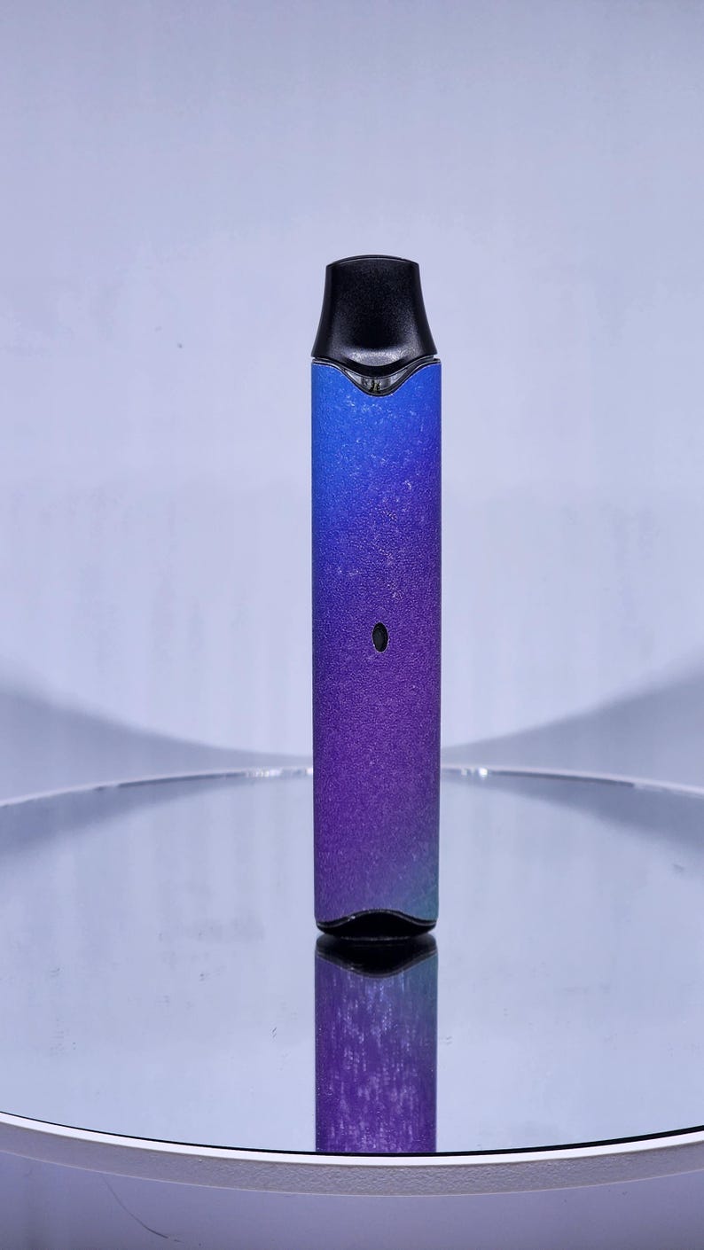 May include: A blue and purple ombre vape pen with a black mouthpiece and a black button on the side.