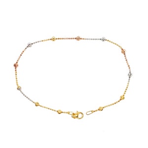 Puede incluir: Un delicado tobillo de oro con un diseño de cadena y pequeñas cuentas redondas en tres colores diferentes: oro amarillo, oro rosa y oro blanco.