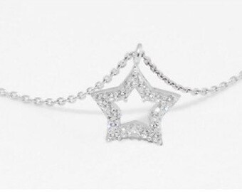 Puede incluir: Un collar de cadena de plata con un colgante en forma de estrella. La estrella está hecha de pequeñas piedras transparentes.