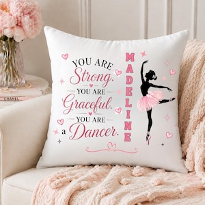 May include: White decorative pillow with pink text and a ballerina silhouette. The text reads "YOU ARE Strong. YOU ARE Graceful. YOU ARE a Dancer." The name "Madeline" is also displayed. Hearts and stars accent the design.