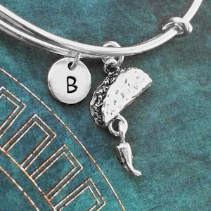 May include: A silver charm bracelet with a silver charm of a taco and a silver charm with the letter B.