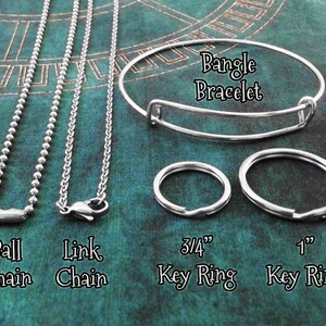 May include: A close-up of five different silver chains and key rings. The chains include a ball chain, a link chain, and a bangle bracelet. The key rings are 3/4 inch and 1 inch in diameter.