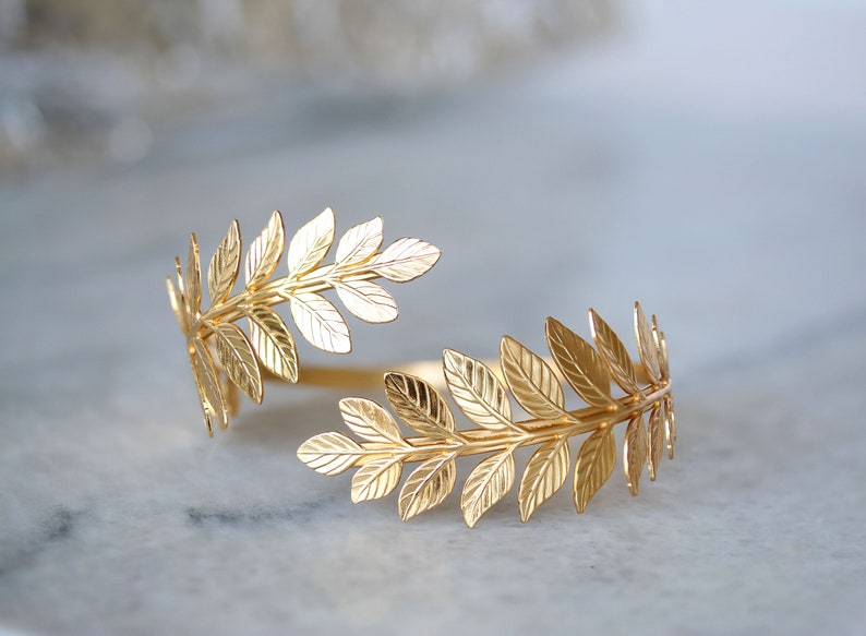 May include: A gold-toned leaf-shaped bracelet. The bracelet is made of metal and has a delicate, feminine design.