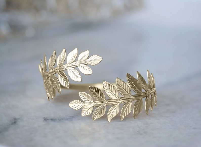 May include: Gold leaf branch ring with a delicate design. The ring is open and adjustable to fit most finger sizes.