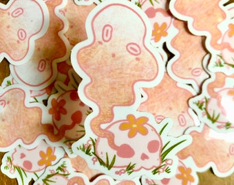 May include: A collection of pink and white stickers featuring a ghost-like figure with a skull and flower design. The stickers are perfect for adding a whimsical touch to any surface.