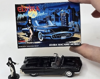 May include: A black Elvira model car kit with a miniature Elvira figure. The box art features a black convertible car and the text "Elvira Mistress of the Dark". The model car is black with white-walled tires.
