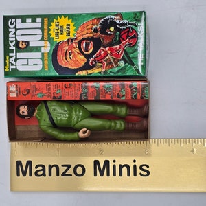 Puede incluir: Una figura de acci&oacute;n vintage Hasbro Talking GI Joe en una caja verde y roja. La figura lleva un uniforme verde y tiene barba marr&oacute;n. La caja dice "&iexcl;Habla!" y "Pelo y barba realistas".
