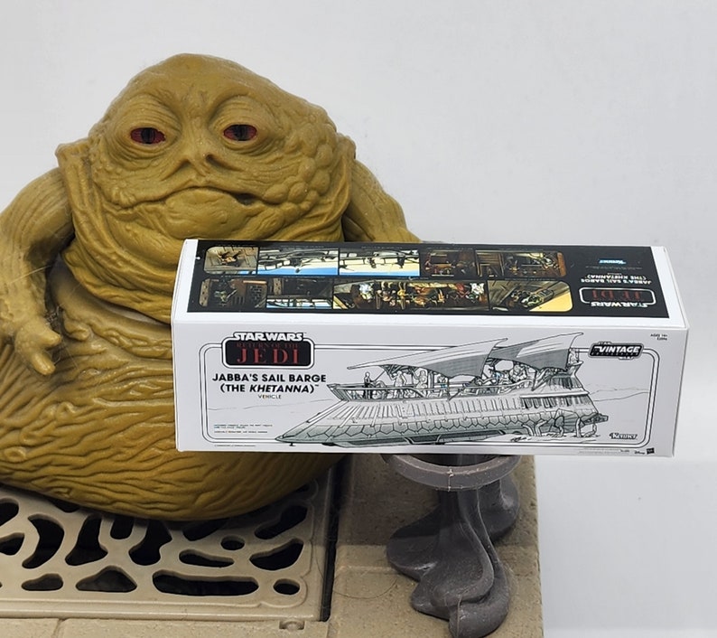 May include: A Star Wars Vintage Collection box for Jabba's Sail Barge (The Khetanna) vehicle. The box is white with black and red text and a black and white illustration of the sail barge.