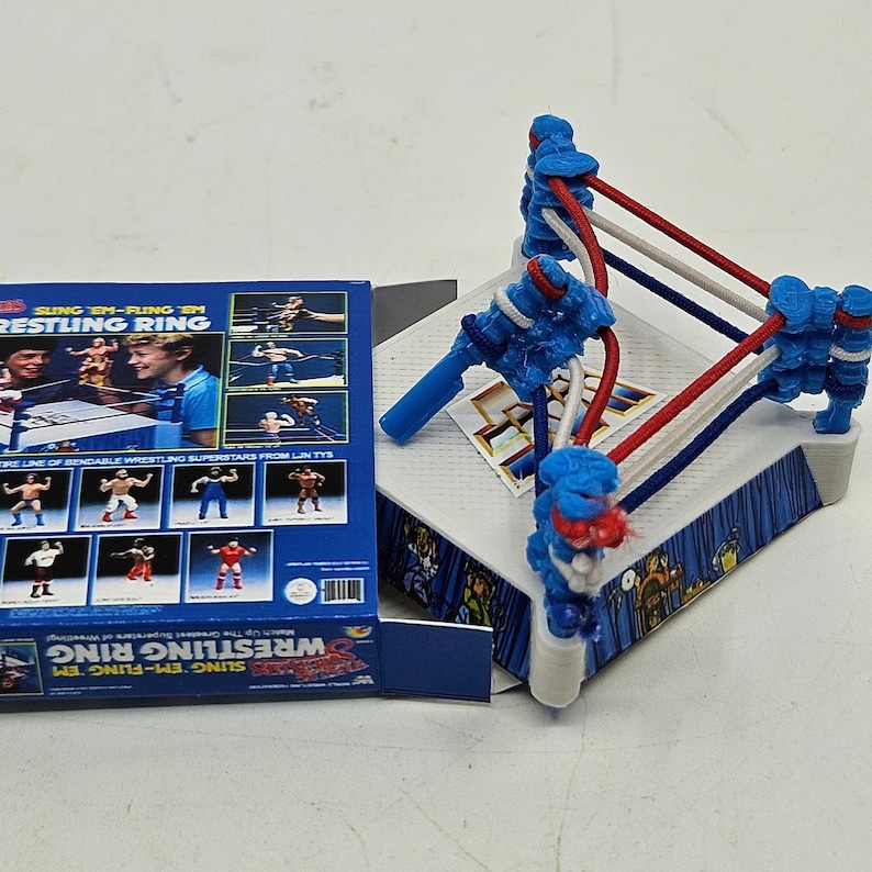 May include: A blue and white wrestling ring toy with red ropes. The box shows a line of bendable wrestling superstars from LJN Toys. The box reads "Sing 'em-Fling 'em Wrestling Ring".