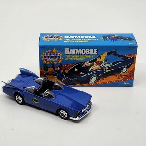 K&ouml;nnte beinhalten: Ein blaues Spielzeug-Batmobil aus Metall aus der Super Powers Collection. Die Schachtel zeigt Batman und Robin im Batmobil mit dem Text "Batmobile The "Caped Crusaders" Action Vehicle!" und "Kenner".