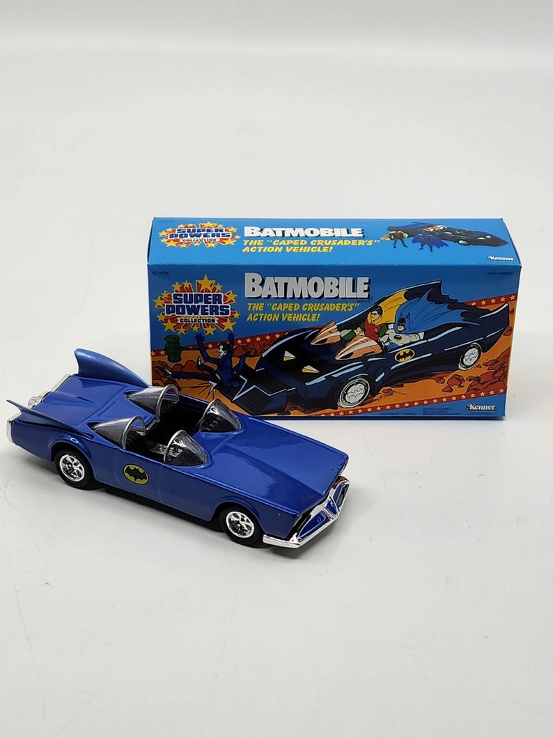 K&ouml;nnte beinhalten: Ein blaues Spielzeug-Batmobil aus Metall aus der Super Powers Collection. Die Schachtel zeigt Batman und Robin im Batmobil mit dem Text "Batmobile The "Caped Crusaders" Action Vehicle!" und "Kenner".