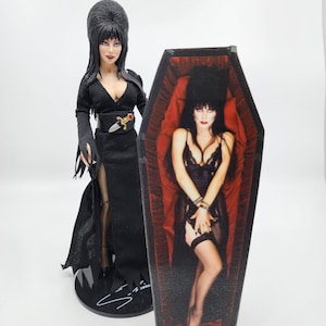 May include: A black and white figure of a woman in a black dress and a red coffin with a black and white image of a woman in a black lingerie. The coffin is decorated with a red interior and a black exterior.