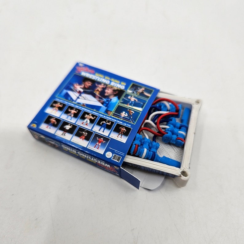 May include: A blue and white wrestling ring toy set with a box featuring images of wrestlers and the text "Join the Fun in Wrestling Ring".