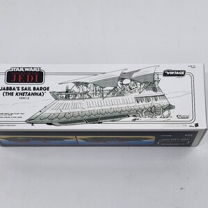 May include: A white box featuring a black and white illustration of Jabba's Sail Barge (The Khetanna) from Star Wars: Return of the Jedi. The box is labelled "Star Wars: Return of the Jedi Vintage Collection" and "Jabba's Sail Barge (The Khetanna)".