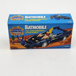 K&ouml;nnte beinhalten: Ein blaues und schwarzes Spielzeug Batmobil aus der Super Powers Collection. Die Schachtel zeigt den Text "BATMOBILE" und "THE "CAPED CRUSADER'S" ACTION VEHICLE!" mit Bildern von Batman und Robin.
