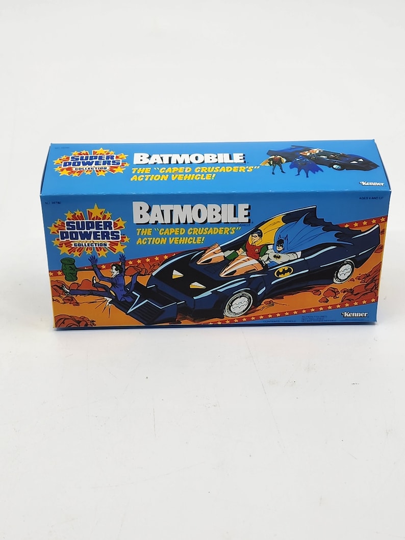 K&ouml;nnte beinhalten: Ein blaues und schwarzes Spielzeug Batmobil aus der Super Powers Collection. Die Schachtel zeigt den Text "BATMOBILE" und "THE "CAPED CRUSADER'S" ACTION VEHICLE!" mit Bildern von Batman und Robin.