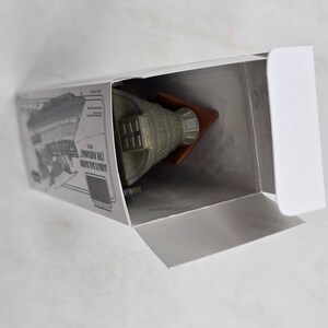 May include: A white box with a grey and green model spaceship inside. The box has a picture of the spaceship on the side and the text "Limited Edition 1:100 Scale Model of the Starship Enterprise".