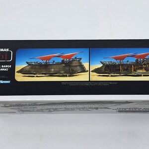 May include: A white box with a red and black Star Wars: Return of the Jedi logo. The box features a picture of Jabba's Sail Barge (The Khetanna) with red sails. The text "Jabba's Sail Barge (The Khetanna)" is printed on the box.