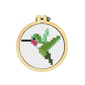 May include: A green and red hummingbird cross-stitch pattern in a wooden embroidery hoop.