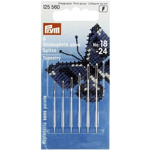 May include: A package of six tapestry needles. The package is blue and white, with the brand name "Frym" at the top. The needles are silver and have large eyes. The package also includes the text "Tapestry" and "No. 18-24".