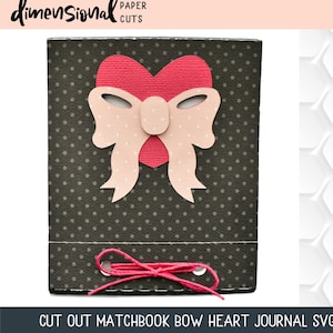 May include: A black card with white polka dots and a pink bow with a red heart in the center. The card has two holes at the bottom with a pink string threaded through them. The text "CUT OUT MATCHBOOK BOW HEART JOURNAL SVG" is at the bottom of the card.